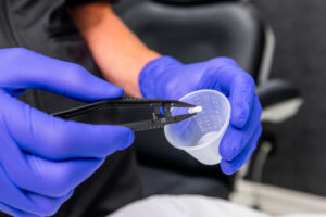 A Karma Beauty & Wellness provider holds a hormone replacement therapy pellet with a pair of tweezers. This metabolism booster in Overland Park corrects age-related hormone imbalances.