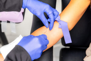 A Karma Beauty & Wellness provider, wearing blue gloves, injects glutathione in Overland Park into a female patient's arm.