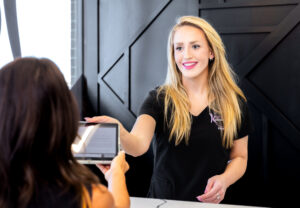 A female Karma Beauty & Wellness provider hands a female patient our consultation tablet for glutathione in Overland Park.